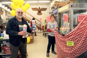 Ernie Latson of Port Angeles, left, purchases the first two bags of popcorn as Swains General Store employee Shawn Price unveils the popcorn machine on Wednesday morning in Port Angeles. The store, which is celebrating its 65th anniversary this year, resumed selling its signature popcorn after a two-year hiatus imposed by COVID-19 health measures. The price remains the same as it was when Swains first offered it to customer in 1966  25 cents. (Keith Thorpe/Peninsula Daily News)