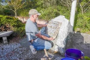 Robert Parker, a self-employed contractor from Port Orchard, installs a granite plaque honoring Navy Seabee Marvin G. Shields, who died in June 1965 in Vietnam and was awarded the Medal of Honor for heroism, at the Marvin Shields Memorial Flagpole on a stone monument from which the original bronze plaque was stolen in 2019. He is very precious to us, said Parker, an ex-Navy Seabee who volunteered to place the plaque. This plaque is granite so there is less incentive for thieves, he added. The Admiralty Inlet Chapter of the Daughters of the American Revolution will dedicate the memorial plaque at 1 p.m. Saturday in the small park on the north side of West Sims Way between Sheridan and Tenth streets. (Steve Mullensky/for Peninsula Daily News)