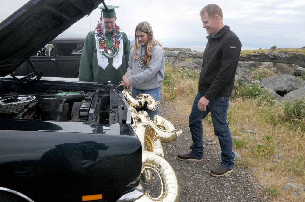 Port Angeles High School graduate Everett Hunsaker, left, watches as sister Emma Hunsaker and father Brent Hunsaker decorate a car at the beginning of Fridays graduation parade through the streets of Port Angeles. (Keith Thorpe/Peninsula Daily News)