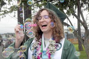 Port Angeles High School graduate Sage Hunter blows bubbles prior to Fridays commencement ceremony at Port Angeles Civic Field. A total of 236 seniors made up the schools Class of 2022. (Keith Thorpe/Peninsula Daily News)