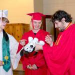 Port Townsend High Schools Duncan Kopala, right, signs the Signature Dog of Cameron Hemsiek, left, as Kenny Mustread, center, waits his turn. Eighty-two seniors received their diplomas before family and friends during the 132nd Commencement at McCurdy Pavilion on Friday night. (Steve Mullensky/for Peninsula Daily News)