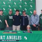Port Angeles football player Daniel Cable signed to play with George Fox University in Newberg, Ore., on Monday. His Roughrider coaches all attended the ceremony. (Pierre LaBossiere/Peninsula Daily News)