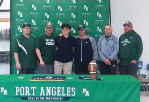 Port Angeles football player Daniel Cable signed to play with George Fox University in Newberg, Ore., on Monday. His Roughrider coaches all attended the ceremony. (Pierre LaBossiere/Peninsula Daily News)