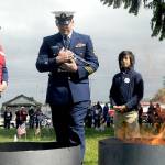 Keith Thorpe/Peninsula Daily News
U.S. Coast Guard Chief Petty Officer Shane Thompson, accompanied by his son, Malachi Thompson, 10, a member Junior American Citizens, carries a used flag for inceneration on Tuesday at the Northwest Veterans Service Center in Port Angeles on Flag Day. Overseeing the burning were Ginny Sturgeon, left, and Jan Urfer, right, members of the Michael Trebert chapter of the Daughters of the American Revolution, which co-hosted the event with the Clallam County Veterans Association. Eleven used cotton flags were burned during Tuesday's Flag Retirement Ceremony.