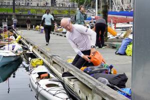 Bob McCall, from Great Britain, loads his kayak with supplies he will need for his 710-mile journey to Ketchikan, Alaska, during the 2022 Race 2 Alaska, which got underway at noon Thursday from Victoria Harbour. A self-described tracker junkie since the first race, McCall decided to enter the race in 2020 and ordered a kayak built in Victoria, but COVID-19 hit and canceled everything. This is the first time he was able to enter and he is looking forward to the adventure. (Steve Mullensky/for Peninsula Daily News)