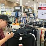A customer checks price tags as she shops at a retail store in Schaumburg, Ill., Thursday, June 30, 2022. (AP Photo/Nam Y. Huh)
