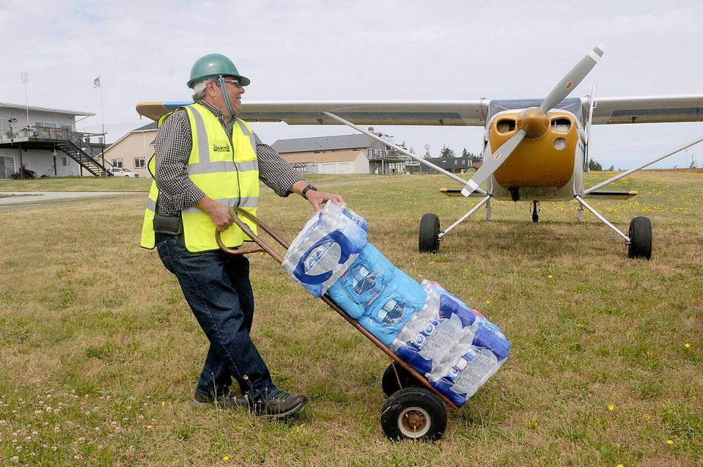 Kevin Deselms transports cases of bottled water after it was airlifted from Port Angeles during a DART training exercise on Saturday at Diamond Point Airport. (Keith Thorpe/Peninsula Daily News)