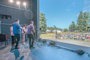 A group of musicians, led by Brandon Godman, in blue shirt, who had never played together before, perform a rousing a set of Bluegrass music to an audience on Littlefield Green at Fort Worden State Park on Saturday. Centrums weeklong Fiddle Tunes Festival ended with this finale concert under the sun. (Steve Mullensky/for Peninsula Daily News)