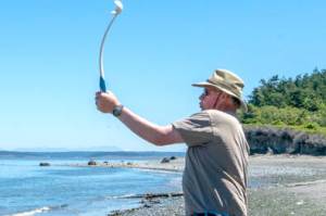 Mike Garling of Port Townsend chucks the ball for his Labradoodle Brody to fetch out of the Strait of Juan de Fuca at North Beach on a sunny day Monday. Temperatures are forecast to be in the mid- to upper 60s for the rest of the week, with some clouds moving in by Friday. (Steve Mullensky/for Peninsula Daily News)