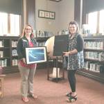 Melody Sky Weaver, on left, accepts a donated Bill Curtsinger photograph from Teresa Verraes, executive director of Northwind Art.