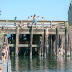 A group of youths cool off by jumping into the cove at the Marine Science Center at Fort Worden State Park on Tuesday. (Steve Mullensky/for Peninsula Daily News)