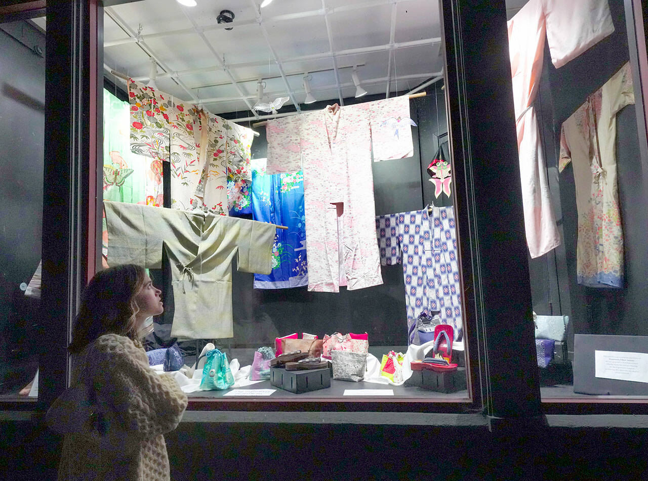 Abbey Engrav, visiting Port Townsend from New York City for her brothers wedding on Saturday, looks at the vintage Japanese garments and shoes on display at the Peninsula Fiber Artists display window on Tyler Street in the Uptown Neighborhood on Friday night. (Steve Mullensky/for Peninsula Daily News)