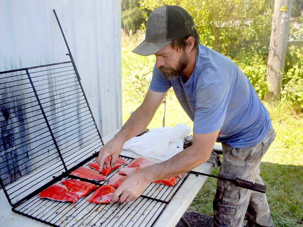 Rick Haartley, president of the Crescent Bay Lions Club, prepares planks of salmon during a benefit salmon feed on Saturday at Joyce Daze. (Keith Thorpe/Peninsula Daily News)