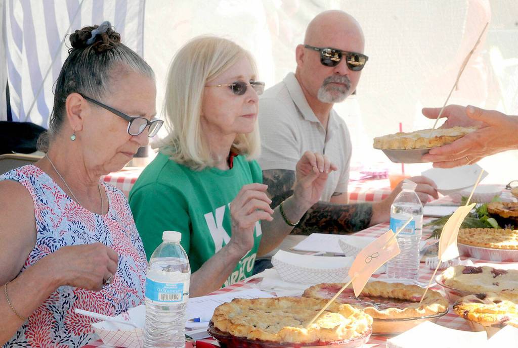 Blackberry pie judges, from left, Blackberry Cafe owner Roxanne Olsen, former Port Angeles Mayor Cherie Kidd and Peninsula Daily News publisher Terry Ward watch as another contest entry is presented to them on Saturday. (Keith Thorpe/Peninsula Daily News)