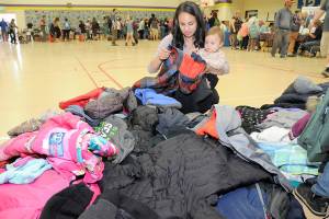 Heidi Eberle of Port Angeles and her daughter, Akira Abbitt, 11 months, sort through a stack of free childrens coats during Saturdays Port Angeles School District Back to School Fair at Jefferson Elementary School. (Keith Thorpe/Peninsula Daily News)