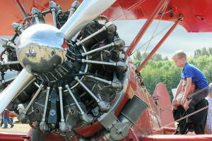 Grayson Kelm, 9, sits on the shoulders of his father, Jon Kelm of Happy Valley, Ore., to get a better look inside the cockpit of a Boeing Stearman PT-17 biplane at Air Affaire on Saturday at Sequim Valley Airport near Carlsborg. The event featured an aircraft fly-in, along with displays, airplane and helicopter rides, a car show, food and live music. (Keith Thorpe/Peninsula Daily News)