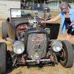 Julie Moen of Port Angeles, right, points the quirks of a rat rod built from a 1928 Ford Roadster by Dennis Broderson of Port Angeles, in drivers seat, during Saturdays Kiwanis Car Show at the Clallam County Fairgrounds in Port Angeles. (Keith Thorpe/Peninsula Daily News)