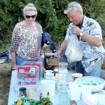Marlene McCurdy of Port Angeles, left, purchases coffee mugs from Gary Gort of Port Angeles at a sale table in front of the Crescent Grange Hall in Joyce on Saturday. (Keith Thorpe/Peninsula Daily News)