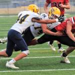 Neah Bay quarterback Julian Carrick is brought down by Naselle's Jack Strange (44) and Kolten Linstrom (14) on Saturday in Forks. Neah Bay shocked the powerhouse Comets 58-20. Lonnie Archibald/for Peninsula Daily News