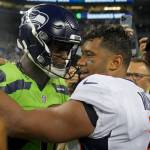 Seattle Seahawks quarterback Geno Smith, left, talks with Denver Broncos quarterback Russell Wilson, right, after an NFL football game, Monday, Sept. 12, 2022, in Seattle. The Seahawks won 17-16. (AP Photo/Stephen Brashear)