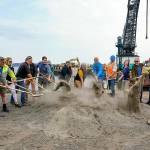 Port Townsend Mayor David Faber, sixth from the left, and other council members and port commissioners toss a ceremonial golden shovel of dirt to break ground on the Point Hudson jetty replacement project on Wednesday at the northern breakwater of the Point Hudson Marina. The marina will reopen in March 2023. After next years Wooden Boat Festival, the south breakwater will receive the same treatment. (Steve Mullensky/for Peninsula Daily News)