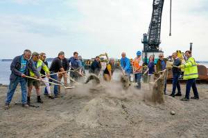 Port Townsend Mayor David Faber, sixth from the left, and other council members and port commissioners toss a ceremonial golden shovel of dirt to break ground on the Point Hudson jetty replacement project on Wednesday at the northern breakwater of the Point Hudson Marina. The marina will reopen in March 2023. After next years Wooden Boat Festival, the south breakwater will receive the same treatment. (Steve Mullensky/for Peninsula Daily News)