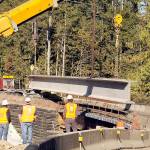A pair of construction cranes prepare on Tuesday to hoist the second of eight 177-foot, 200,000-pound concrete girders that will support a new bridge being constructed on U.S. Highway 101 over Indian Creek southwest of Port Angeles. (Keith Thorpe/Peninsula Daily News)