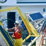 A technician works on the monitoring equipment housed on the buoy onboard the U.S. Coast Guard Cutter Henry Blake in the Strait of Juan de Fuca on Sept. 20. The buoy, part of the National Oceanic and Atmospheric Administrations network of weather monitoring stations, stopped transmitting weather data last year. Technicians replaced the monitoring equipment last week. (Peter Segall / Peninsula Daily News)