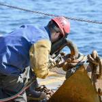 A crew member of the U.S. Coast Guard cutter Henry Blake cuts the chain off of an anchor used to hold a National Oceanic and Atmospheric Administration weather buoy in place in the Strait of Juan de Fuca on Tuesday, Sept. 20. Crews replaced several parts of the buoy, including the chain and rope used to keep it in place. (Peter Segall / Peninsula Daily News)