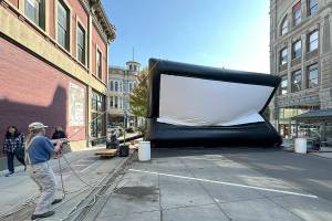 Miles McRae, owner of Full Spectrum Projector and Sound and of the Airscreen, pulls the ropes to control the 15-foot by 30-foot screen as air is pumped into the screen to inflate it for use during the 23rd Port Townsend Film Festival, which started on Thursday. (Steve Mullensky/for Peninsula Daily News)