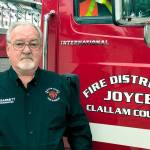 Clallam County Fire District No. 4)  
The late Terry Wayne Barnett, who was a Joyce Fire District Commissioner and chair of the building committee, is pictured standing in front of one of the fire trucks he wanted to be housed in the planned apparatus barn in Joyce.