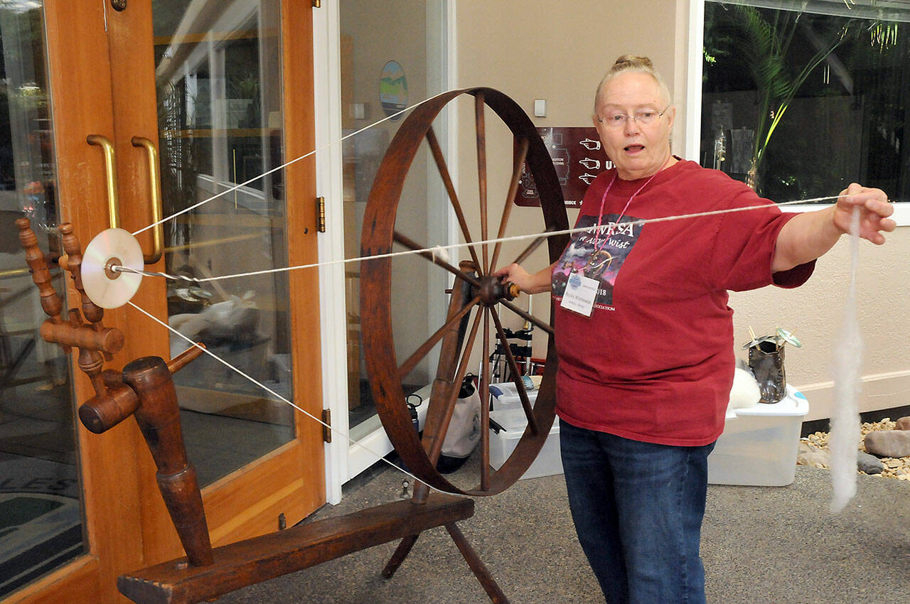 Rocky Wisniewski of Sequim, a member of the North Olympic Shuttle Spindle Guild, demonstrates how to spin fiber on a walking wheel during Saturdays Pacific Northwest Fiber Exposition at Vern Burton Community Center in Port Angeles. The two-day event featured a wide variety of demonstrations, exhibits, workshops and a marketplace showcasing all things fiber. (Keith Thorpe/Peninsula Daily News)