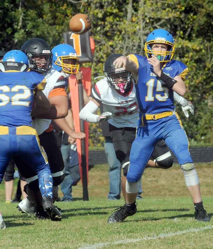 Crescent quarterback Henry Bourm passes as teammate Tommy Leonard, left, blocks the Neah Bay defense on Saturday. Bearing down from behind is Neah Bays Adan Ellis. (Keith Thorpe/Peninsula Daily News)