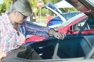 Wendy Davis of Port Townsend takes a look under the hood of her Rivian truck, where an empty storage area is where the engine would have been on a gasoline-powered car. The Rivians battery is on the bottom of the truck, much like a skateboard, Davis said. The vehicle can travel 320 miles on a charge, she added. (Diane Urbani de la Paz/For Peninsula Daily News)