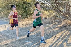 Port Angeles' Max Baeder runs ahead of a Kingston competitor during Wednesday's Olympic League meet at the Dungeness Recreation Area near Sequim.