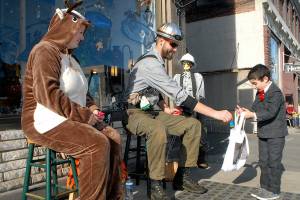 Keith Thorpe/Peninsula Daily News
Six-year-old Emmett Stratford of Port Angeles receives a treat from Sarah Ogerly, owner of Olympic Stauned Glass, left, and Mitch Zenobi during Halloween trick or treating in downtown Port Angeles in 2019.