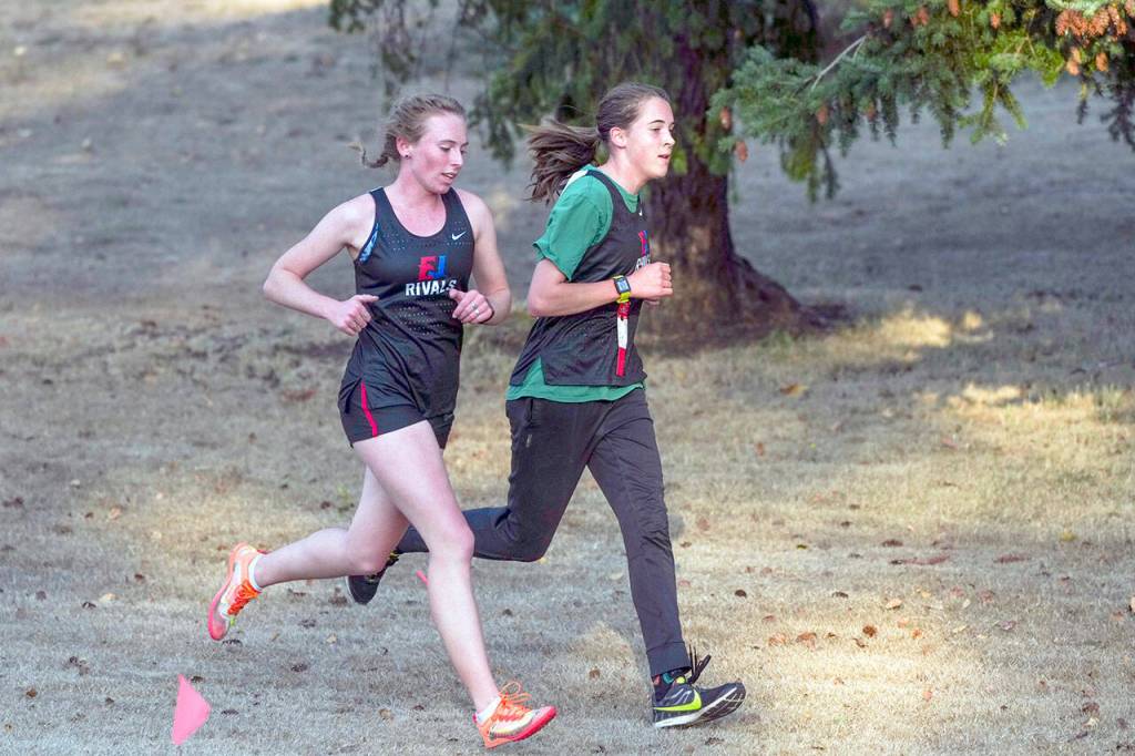 Steve Mullensky/for Peninsula Daily News East Jefferson Rivals Camryn Hines, left, and Fiona Fraser match stride for stride during the first lap of a two lap 5K Cross Country course during a seven school meet at Port Townsend Golf Course on Tuesday. Hines finished the race in third with a time of 20:40 and Fraser came in fourth with a time of 21:05.