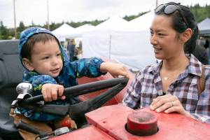 Vanessa Wade and her son enjoy the Chimacum Farmers Market earlier this season. Sunday is the last day before next summer. (David Conklin)