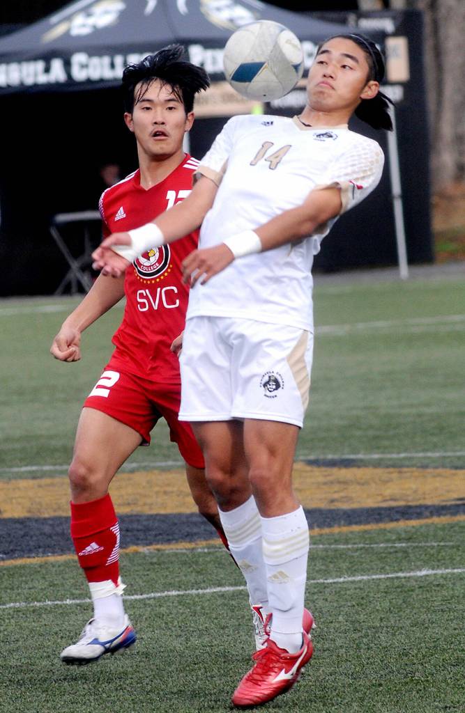 Peninsulas Shu Kato, right, brings down a flying ball as Skagits Shingo Yamada keeps watch during Saturdays match in Port Angeles. (Keith Thorpe/Peninsula Daily News)