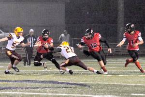 Lonnie Archibald/for Peninsula Daily News
Neah Bay's Jullian Carrick (5) looks for running room against Winlock Friday night on the Spartan Stadium turf in Forks during this Class 1B playoff game.  Also in the action are Red Devils Charles Halttunen (12) and Jodell Wimberly (1).  Winlock's Dalton Noyes ( 54) and Logan Hall (20) were on the defense.