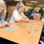 Puzzle solvers, from left, Mary Latson, Kandi Latson and Laura Arndt, all of Port Angeles, attempt to assemble a picture puzzle during a competition on Saturday at the Port Angeles Public Library. The competition pitted about a dozen teams in a timed event to see who could assemble a 500-piece puzzle the quickest, or if the clock expired, which team had the fewest pieces left to place. (Keith Thorpe/Peninsula Daily News)