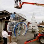 An oversized ornament for the opening ceremony at 5 p.m. Wednesday for the 32nd annual Festival of Trees this coming weekend is put in place on Sunday at the Vern Burton Community Center in Port Angeles, with volunteer Ricki Smith in the bucket, Matt Williams working inside the 14-foot-tall ornament and Laci Williams watching. Four of the huge round ornaments, a 20-foot-tall tree and two fountains donated by Microsoft to the Olympic Medical Center Foundation, will be lit up outside the community center during a free 20-minute ceremony that also will include performances by the Port Angeles Symphony, Ballet Workshop and Ghostlight Productions. A limited number of tickets, which will provide seats under cover outside and a sneak preview of the trees to be auctioned off on Friday, are available for $20 by going to omcf.org. (Dave Logan/for Peninsula Daily News)