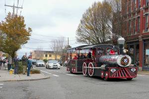 People stop and take pictures of the Port Townsend Kiwanis George Earl Memorial Cho Cho as it clangs along Water Street in downtown Port Townsend on Small Business Saturday. The popular Choo Choo made a circuit from the American Legion to Uptown and back again, delighting passengers and spectators alike. (Steve Mullensky/for Peninsula Daily News)