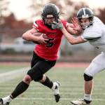 Maria Dorsten/for Peninsula Daily News
Neah Bay quarterback Julian Carrick is facemasked by a Liberty Christian defender on one of his big runs Saturday in the state 1B semifinals held at Mount Tahoma High School in Tacoma. Carrick scored six touchdowns as Neah Bay won 82-24. The Red Devils will face Liberty Bell next week in the championship game.