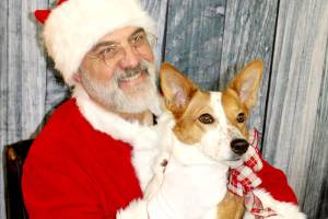 Santa, Christopher Thomsen, holds Lizzie on Sunday at Airport Garden and Nursery in Port Angeles as part of a fundraiser for the Peninsula Friends of Animals. More than a dozen dogs, some more wiggly than others, sat in Santas lap for a photo. (Dave Logan/for Peninsula Daily News)