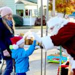 Erin Kluck of Port Townsend watches as her son Kaspar, 4, gives Santa Claus a high five during Saturdays Uptown Port Townsend Farmers Market. Santa, aka Bryan Hood, said hell be manning the Crusty Crumb bakery table again, as the last two farmers markets of the year happen this Saturday and on Dec. 17. (Diane Urbani de la Paz/For Peninsula Daily News)