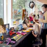Molly Brown of Port Angeles, and her children, Lucy Brown, 3, and Oliver Brown, 5 months, examine a display of locally-produced art items for sale as gifts on Thursday during the holiday Makers Market at the Port Angeles Fine Arts Center. (Keith Thorpe/Peninsula Daily News)