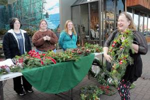 Louisa Monger of Port Angeles, right, shows off a handmade wreath she was purchasing at tables staffed by members of the Port Angeles High School Choir, including seniors, from left, Kaelyn Herringer, Rayna Mathison and Grace Possinger, on Saturday at the Conrad Dyar Memorial Fountain in downtown Port Angeles. The wreath sale was a benefit to help fund a spring trip to perform at Carnegie Hall in New York with members of the schools choir, orchestra and band. Leftovers from Saturdays sale, along with a bake sale and silent auction, will be available during the schools holiday concert at 7 p.m. tonight at the Port Angeles Performing Arts Center, 304 E. Park Ave. (Keith Thorpe/Peninsula Daily News)