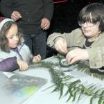 Amdiya Miller, 4, of Port Angeles gets assistance from Breanna Hedtke with making a decorative headdress at an activity table in Websters Woods at the Port Angeles Fine Arts Center during Saturdays Wintertide Festival of Lights. (Keith Thorpe/Peninsula Daily News)