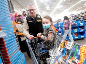 Brian King, the chief criminal deputy for the Clallam County Sheriffs Office, is among more than 100 volunteers from a dozen agencies to participate in the Shop with a Hero program at Wal-Mart in Port Angeles. About 80 kids from the community got to go on a shopping spree with law enforcement officers from Port Angeles, Sequim and other agencies and spend $100 however they wished. They also had a chance to take photos with Santa, sip on hot chocolate, decorate cookies and see police vehicles up close. (Jesse Major/for Peninsula Daily News)